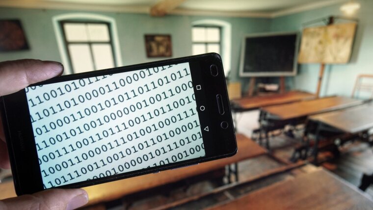 Symbolfoto: Text in  Binärcode auf dem Display eines Smartphones